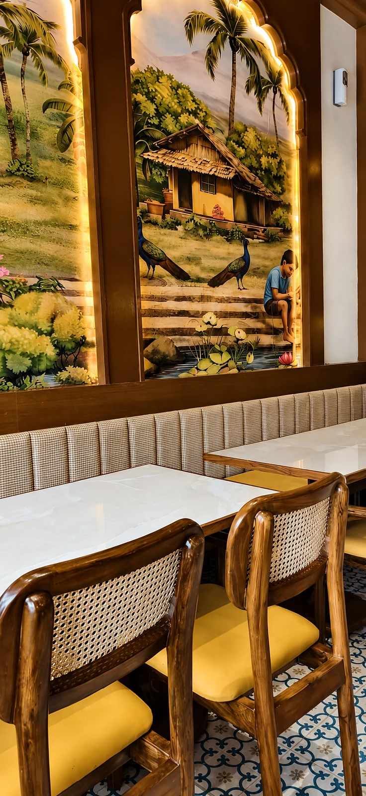 Hand-painted South Indian village mural above polished cane dining chairs