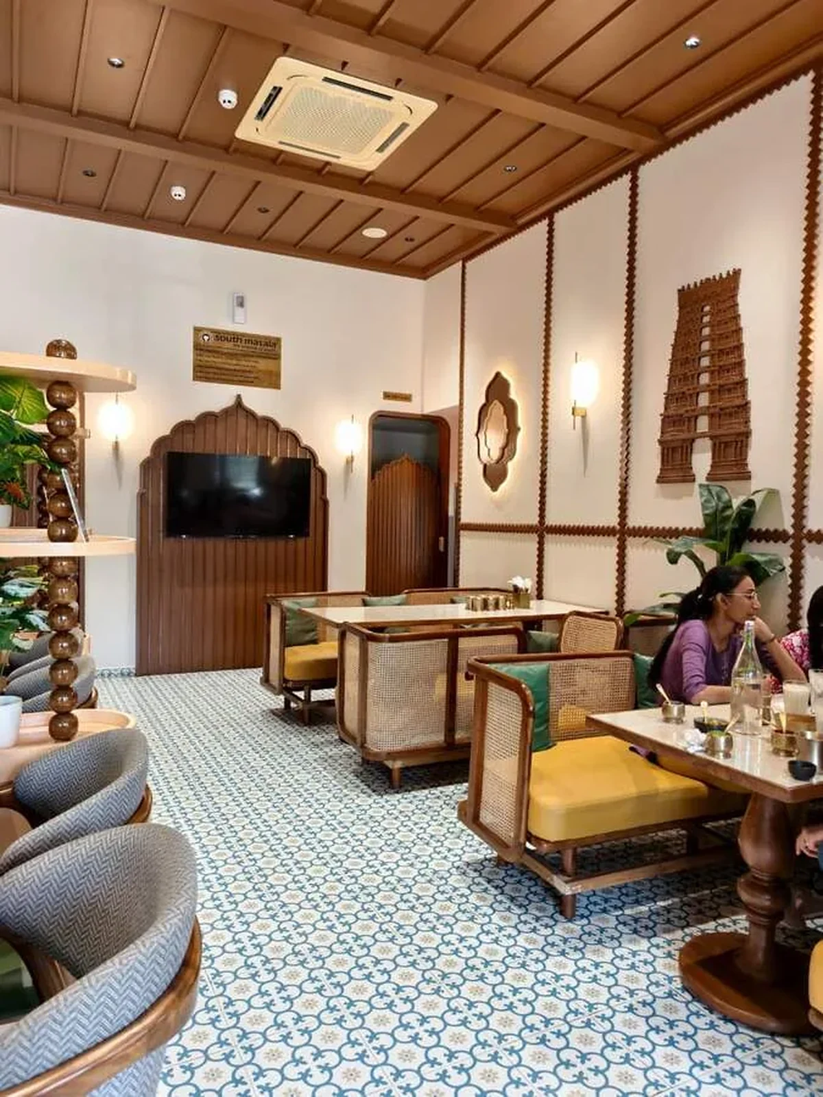 An inviting South Masala interior with handcrafted woodwork and a temple motif